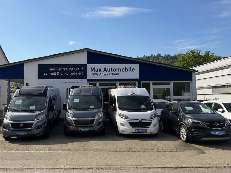 Gebrauchtwagen vor der Halle mit Schild „Max Automobile PKW An-/Verkauf“